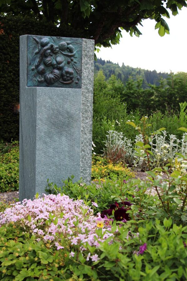 Gedenkstein mit Bronzerelief im Blumenbeet