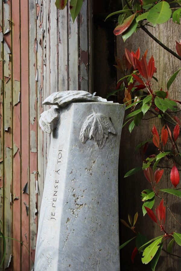 Heller Gedenkstein mit Blattrelief im Herbst