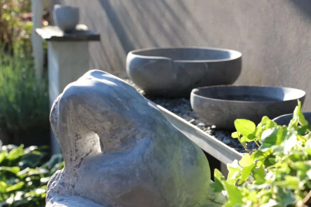 Tierskulptur und Steinschalen im Garten des Ateliers