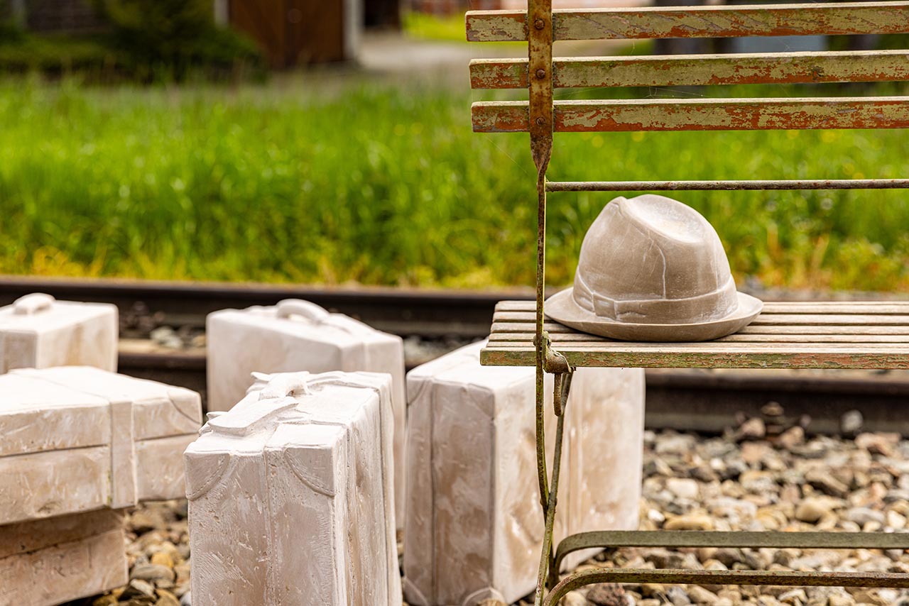 Koffer aus Stein und Hut auf dem Areal beim Atelier