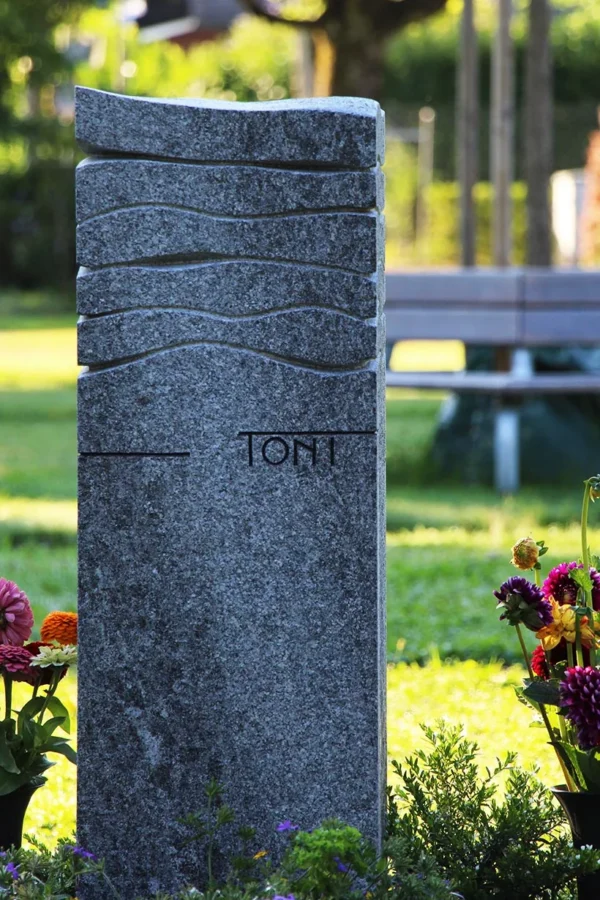 Schlanker Gedenkstein aus Granit mit Wellenlinien