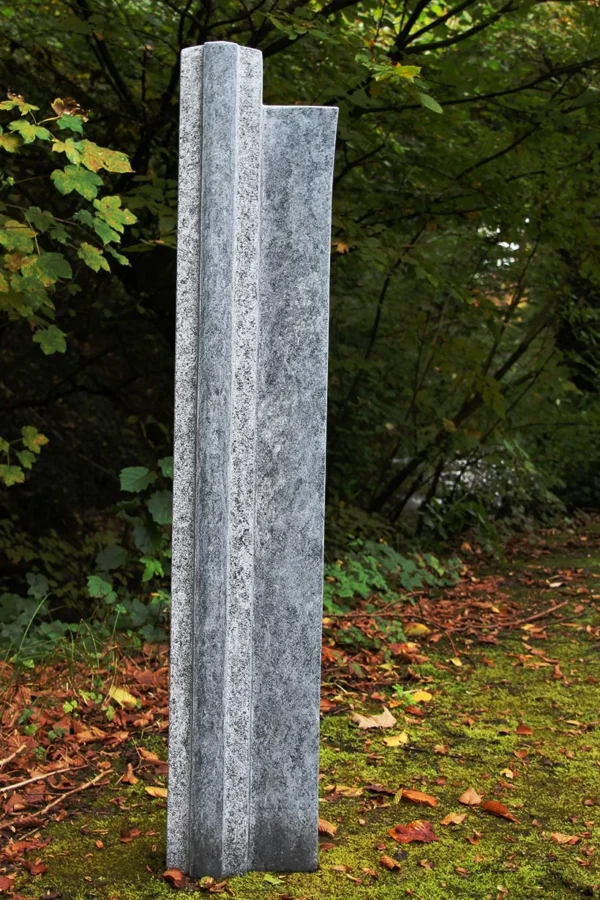 Hohe, zweiteilige Gedenkstele aus Stein im Herbstlaub
