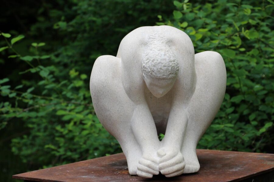 Hockende Figur aus hellem Stein