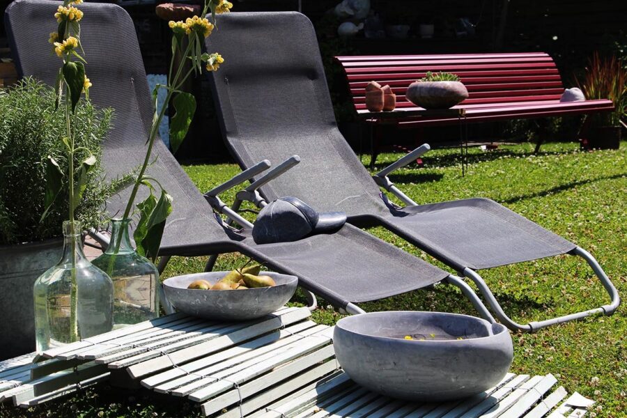 Steinschalen im Garten neben Liegestühlen
