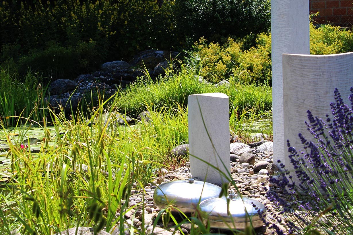 Helle Skulpturen im Garten mit Lavendel
